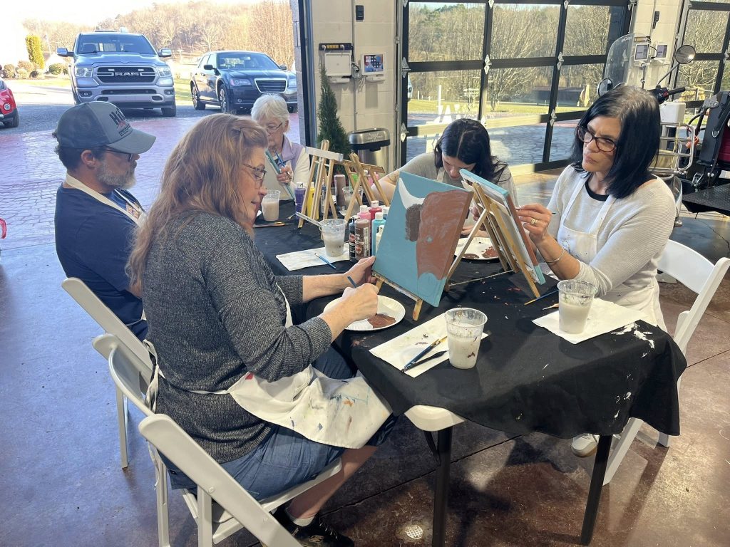 A group of people seated at a table inside a barn during what appears to be a tasting or event.