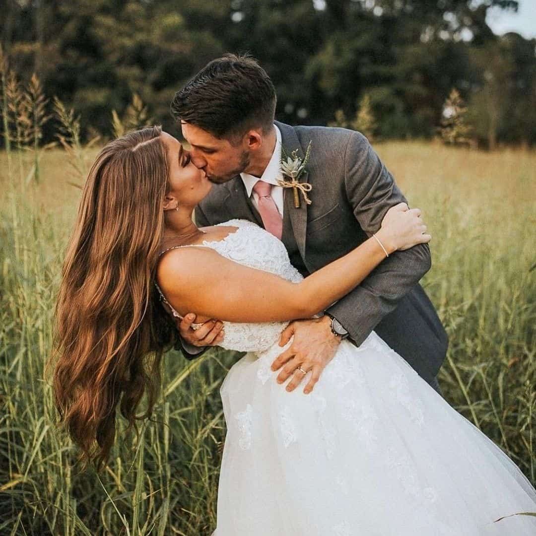 A couple kissing in the tall grass of the Field G Hay Field
